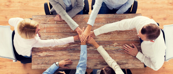 Team aan tafel met handen op elkaar