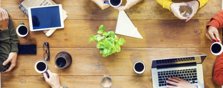 Team vanaf bovenaf (met laptop en koffie aan tafel)